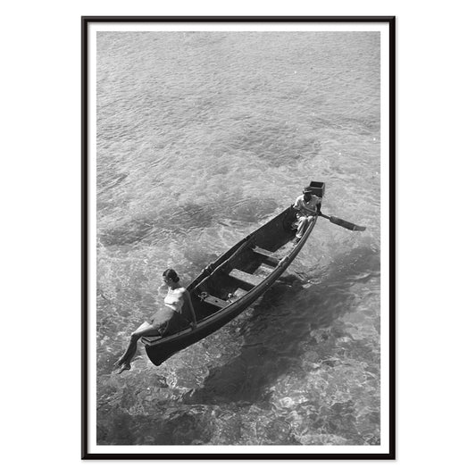 Fashion model on boat edge with man rowing in clear water Montego Bay Jamaica by Toni Frissell artwork poster, with black aluminium frame on white background