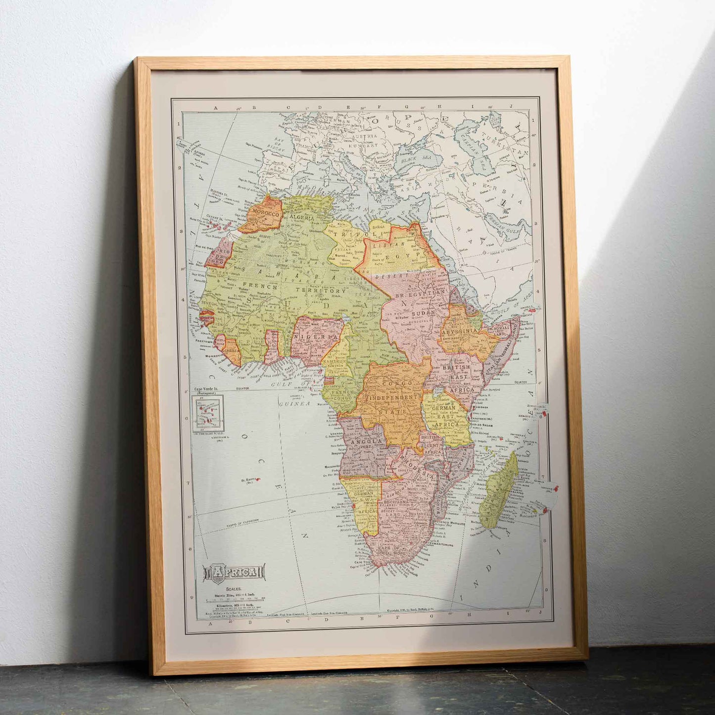 Rand McNally and Company Africa Map vintage poster of the African continent in muted green yellow pink and beige tones, with wooden magnetic frame on white background