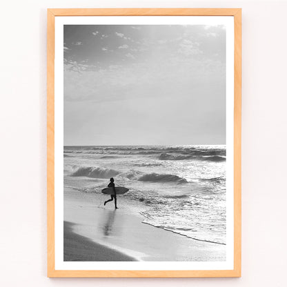 Black and white poster of a surfer with a board entering the ocean titled Surfer in Portugal by artist Black, framed and displayed in modern living room decor