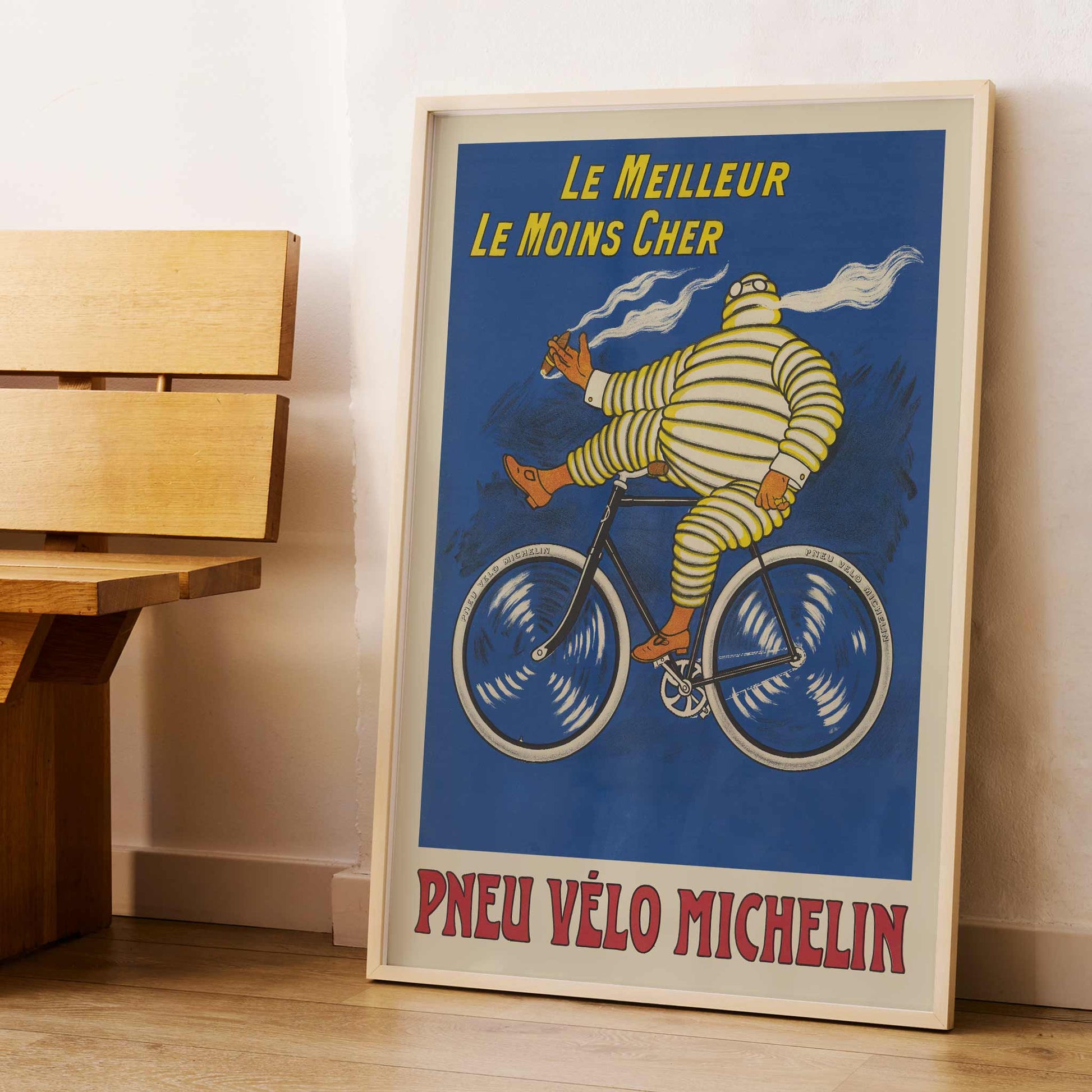 Marius Rossillon Michelin bicycle tire poster with striped cyclist riding bicycle on blue background with yellow text, with wooden magnetic frame on white background