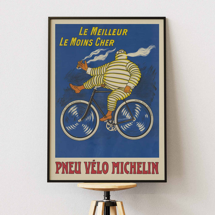 Marius Rossillon Michelin bicycle tire poster with striped cyclist riding bicycle on blue background with yellow text, framed and displayed in modern living room decor