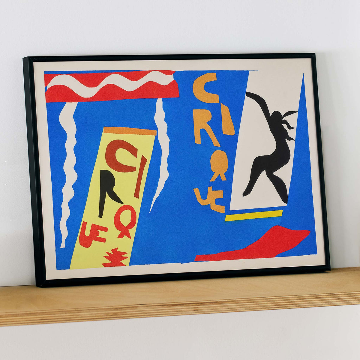 Henri Matisse Cirque poster with black acrobat silhouette, cut-paper circus lettering and white streamers on blue, with wooden magnetic frame on white background