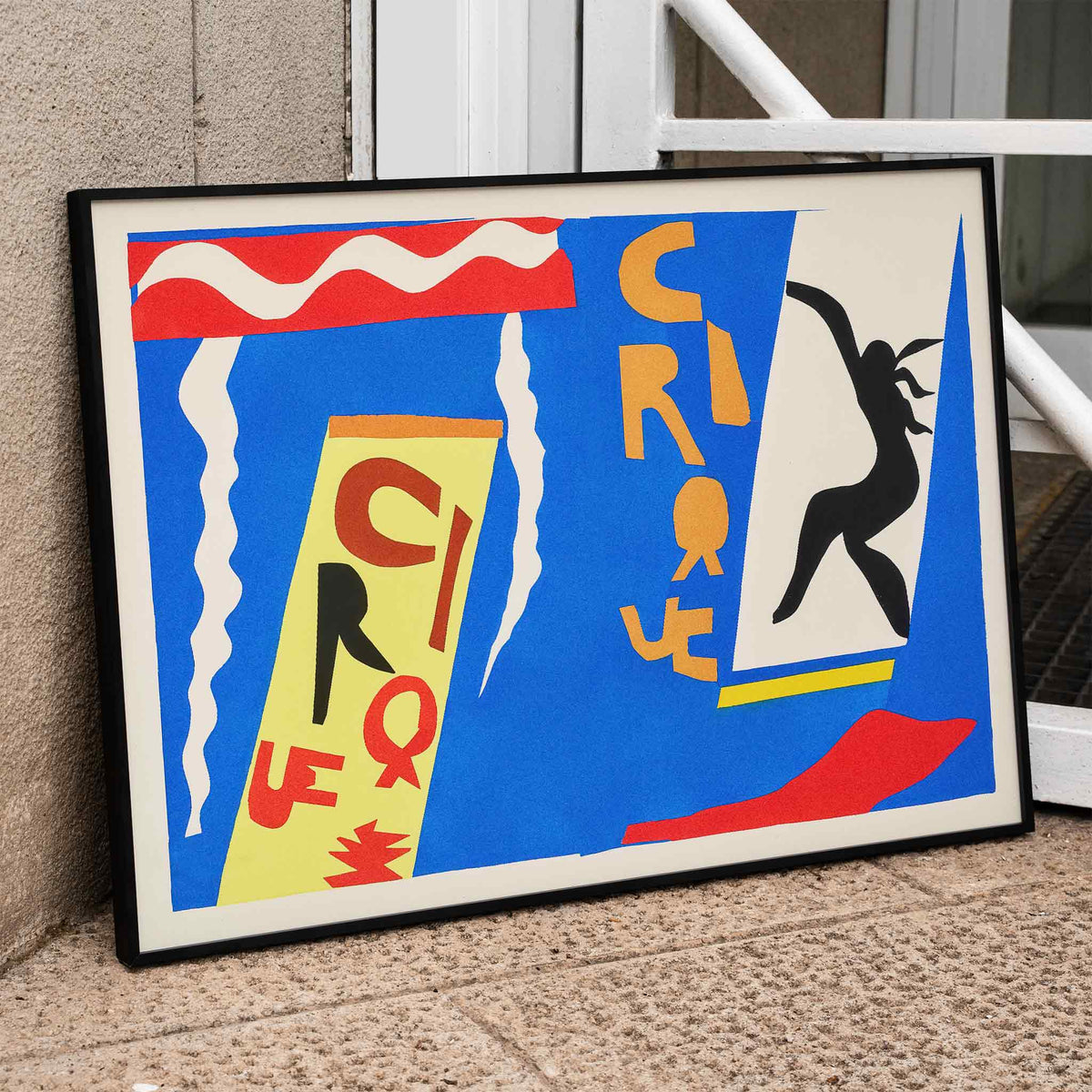 Henri Matisse Cirque poster with black acrobat silhouette, cut-paper circus lettering and white streamers on blue, framed and displayed in home decor