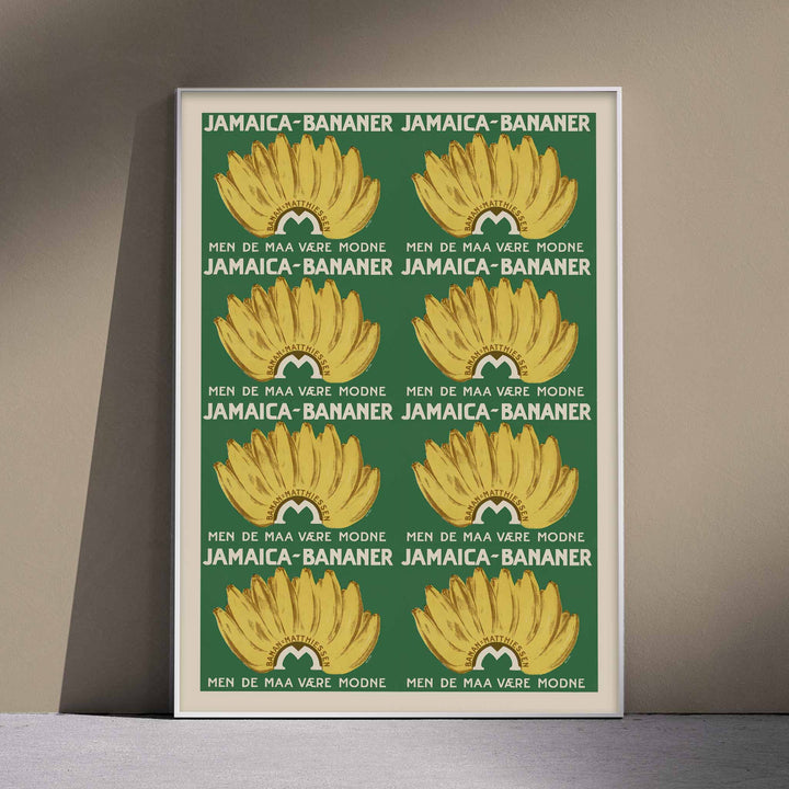 Jamaica Bananas poster with repeated ripe yellow banana bunches on a deep green vintage advertising design, with wooden magnetic frame on white background