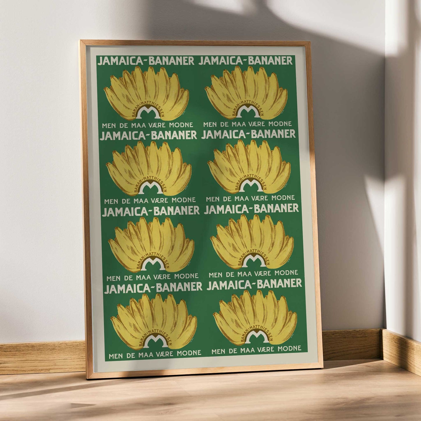 Jamaica Bananas poster with repeated ripe yellow banana bunches on a deep green vintage advertising design, framed and displayed in modern living room decor