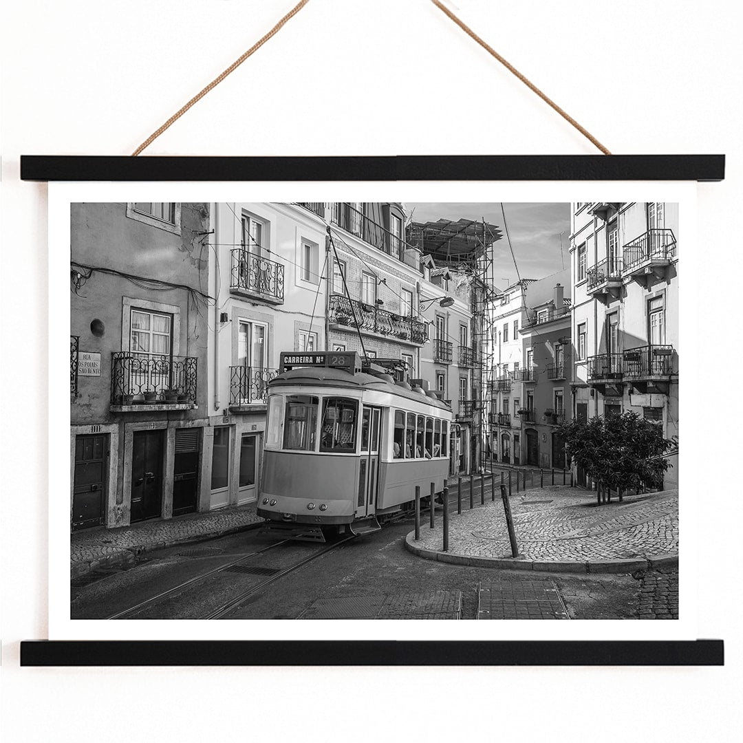 Lisbon Tramway 28 Black and White historic tram navigating cobblestone streets in Lisbon street scene poster, with wooden magnetic frame on white background