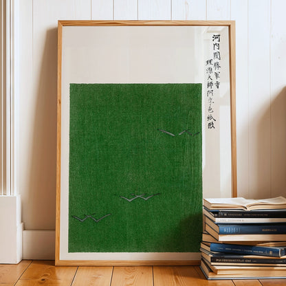 Minimalist Japanese vintage woodblock print poster of green field with birds by Taguchi Tomoki from Yatsuo no tsubaki, framed and displayed in modern living room decor
