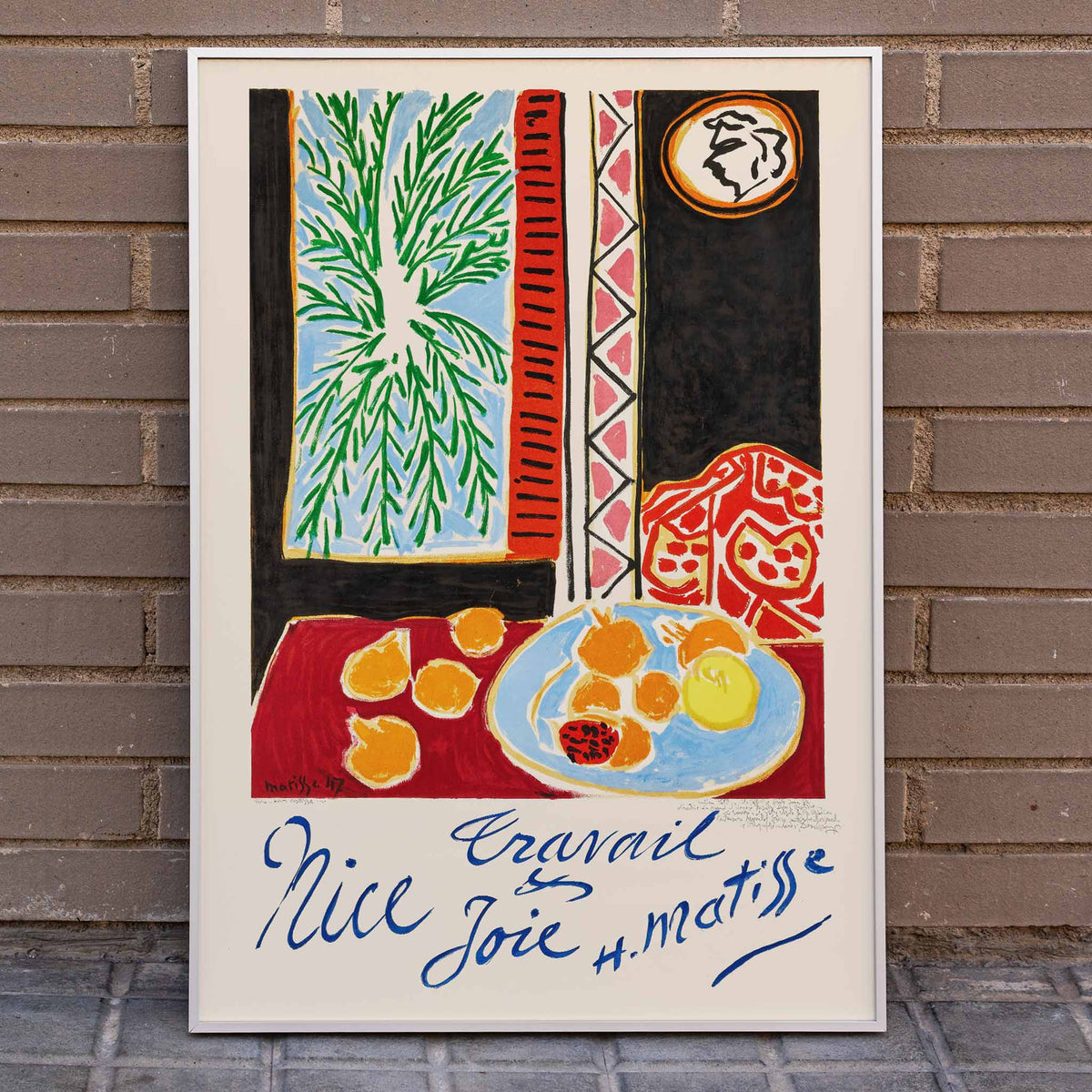 Henri Matisse Nice Travail et Joie poster with palm fronds, fruit on a blue plate, and bold red and black shapes, framed and displayed in home decor