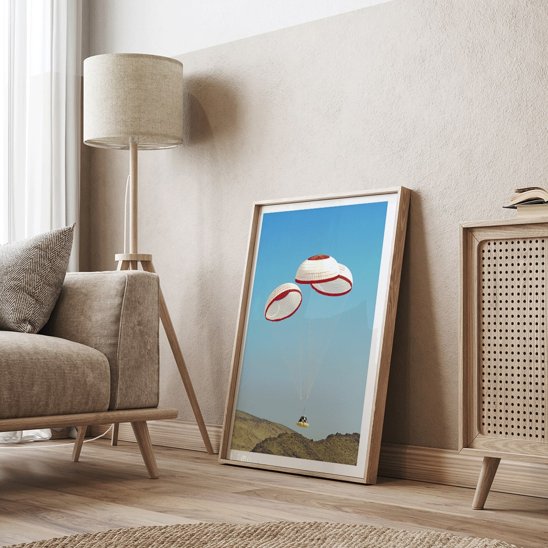 CST-100 crew capsule landing with three parachutes over desert landscape by NASA and The Boeing Company poster artwork, framed and displayed in home decor