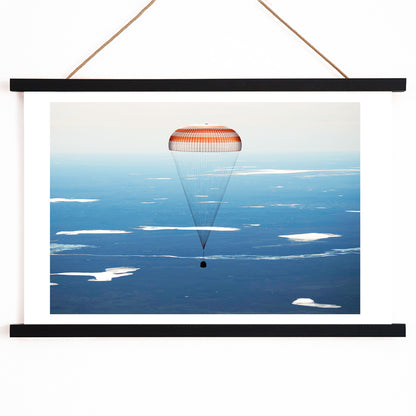 Soyuz MS-02 spacecraft descending with parachute over Kazakhstan NASA poster artwork showing landing, with wooden magnetic frame on white background