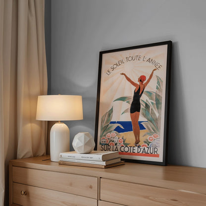 Woman in swimsuit enjoying sunny beach scenery surrounded by flowers Cote dAzur artwork by Roger Broders, framed and displayed in modern living room decor