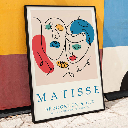 Line art portrait and poster inspired by Matisse Papiers decoupes featuring colorful abstract shapes faces in blue red and yellow with text at the bottom, framed and displayed in home decor
