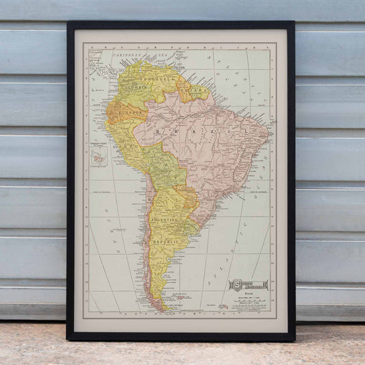 Vintage Rand McNally South America map poster with labeled continent in soft yellow pink and beige cartographic detail, framed and displayed in home decor