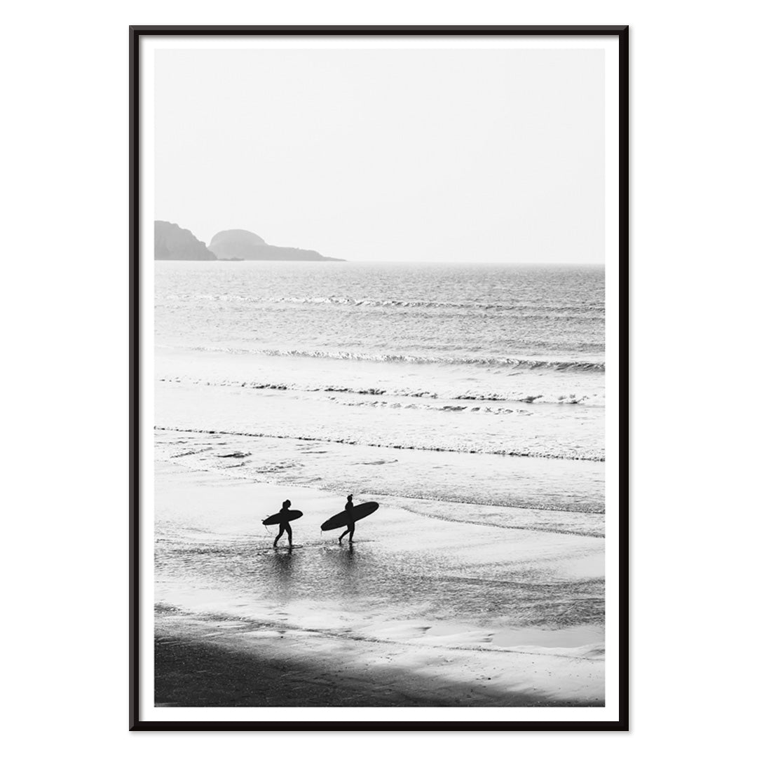 Black and white poster of surfers walking along the beach Surfers walking on the beach artwork, with black aluminium frame on white background